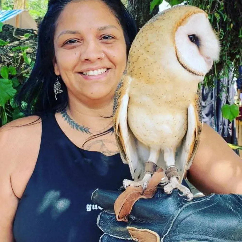Bruxa Lorena sorrindo com uma coruja pousada na luva