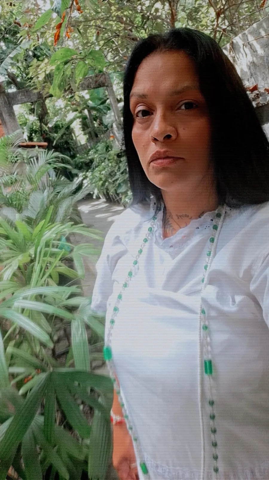 Ingrid Lorena Costa, a Bruxa Lorena, de branco com guias verdes no jardim do templo