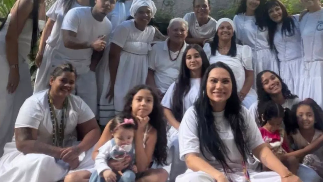 Famílias do templo vestidas de branco, com crianças e um bebê no colo, sentadas no quintal