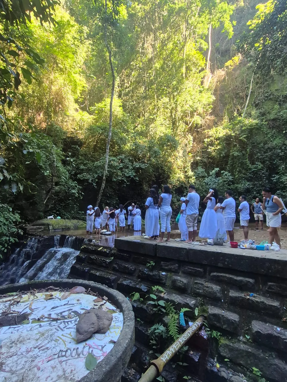 Filhos da casa vestidos de branco em gira na beira da cachoeira, na mata