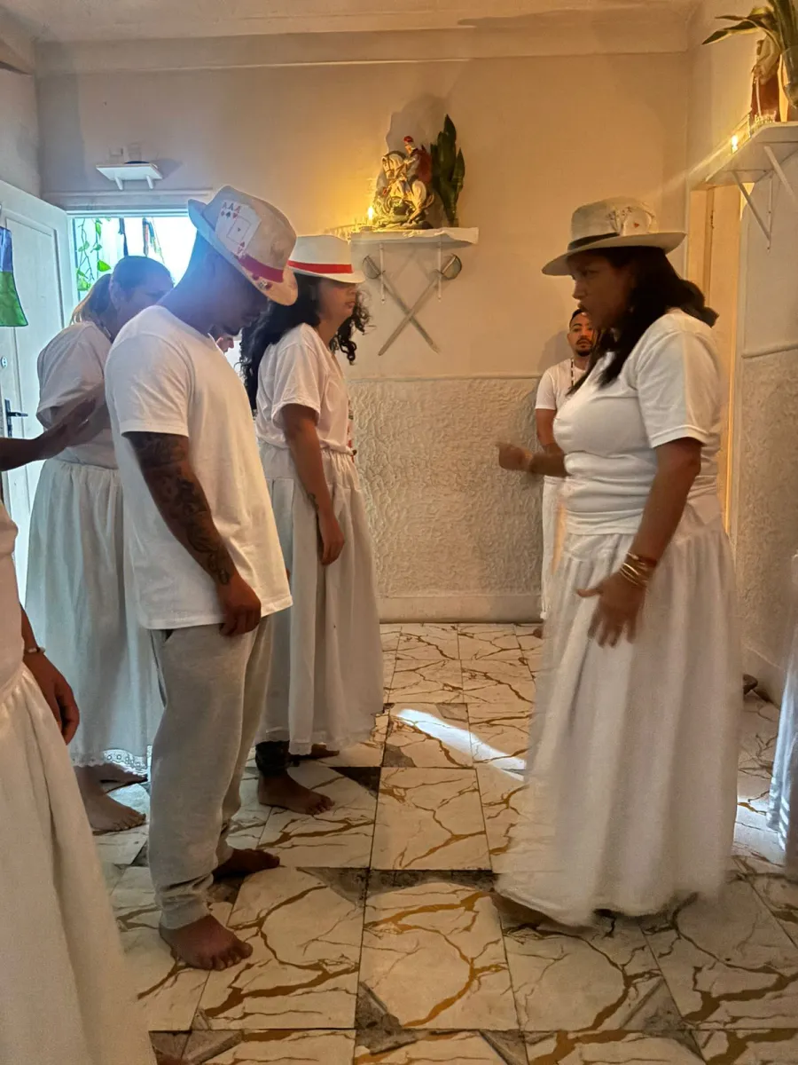 Gira de malandros no templo, com médiuns de branco usando chapéus de palha