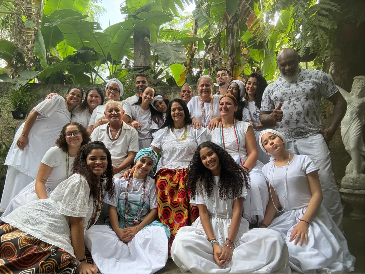 Família do templo reunida de branco no quintal, entre plantas