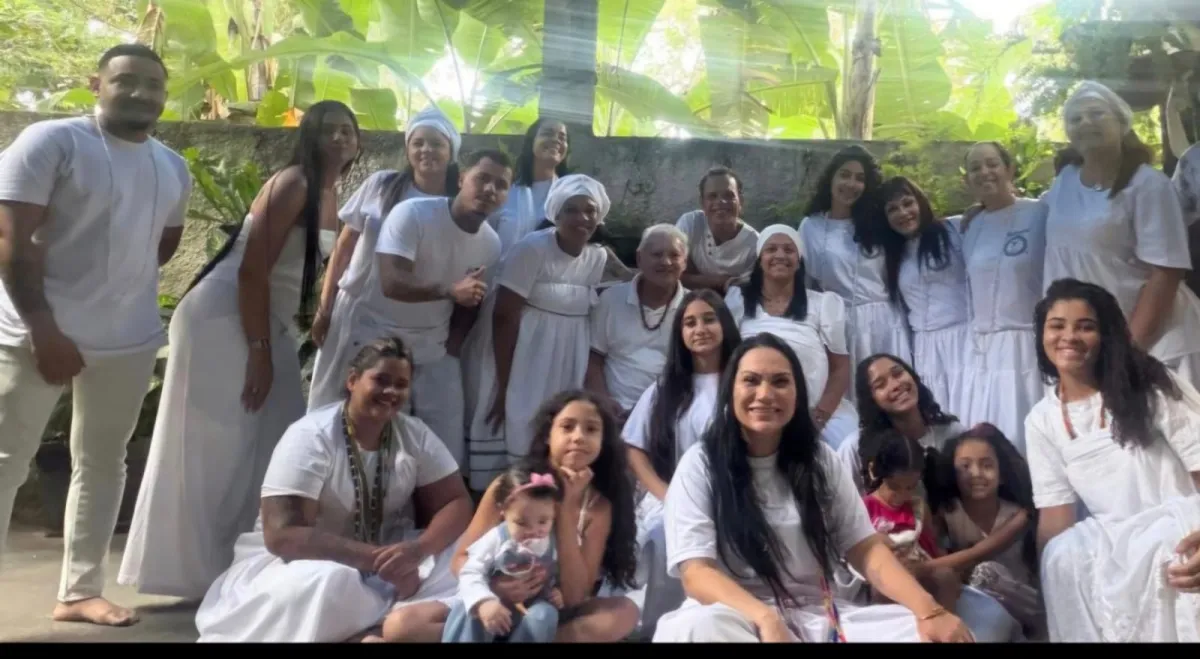 Filhos e filhas do templo reunidos de branco no quintal entre plantas