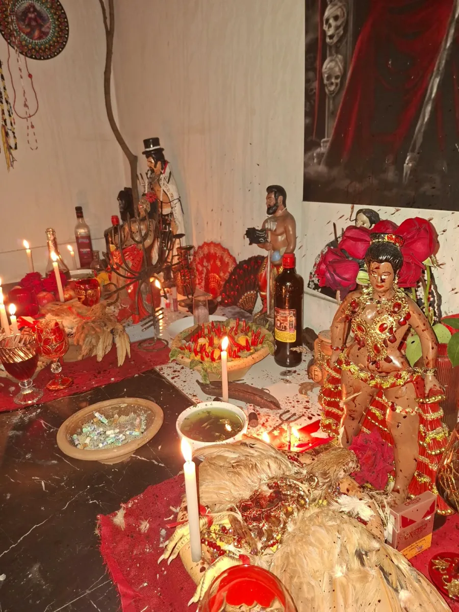 Altar de Maria Padilha com rosas vermelhas, velas acesas, taças e imagens