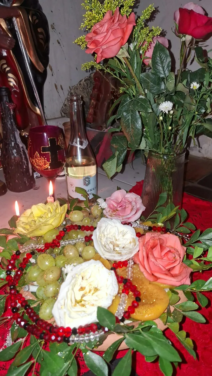 Oferenda de rosas vermelhas, brancas e cor de rosa com uvas e guias vermelhas